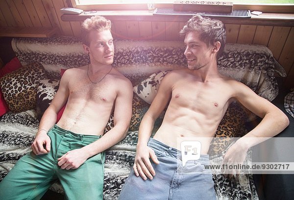 Zwei junge Männer liegen nackt auf dem Bett.