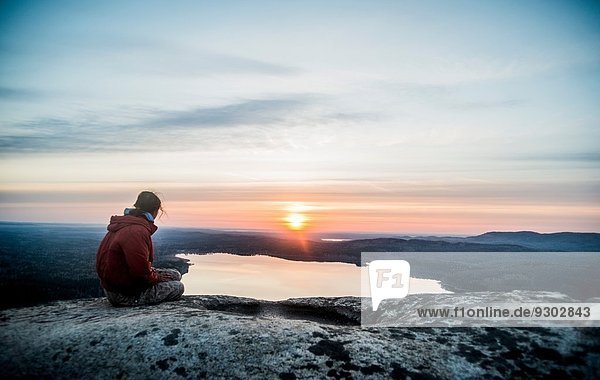 Junge Wanderin mit Blick auf den Sonnenuntergang über dem fernen See