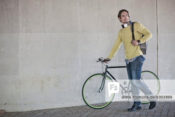 Mittlerer Erwachsener Mann schiebt Fahrrad durch Stadtunterführung
