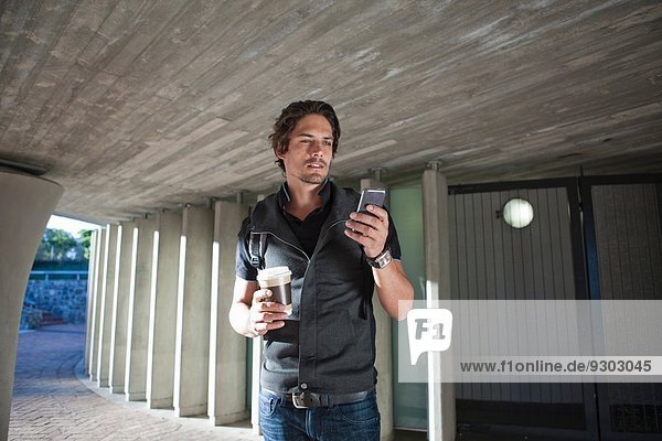 Mid Erwachsene Mann SMS auf Smartphone in der Stadt Unterführung