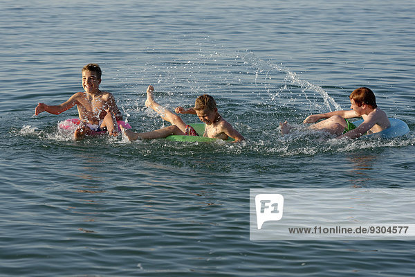 Water fight  children playing on floating tyres in the sea  Mediterranean  near Fano  Marche  Adriatic  Italy