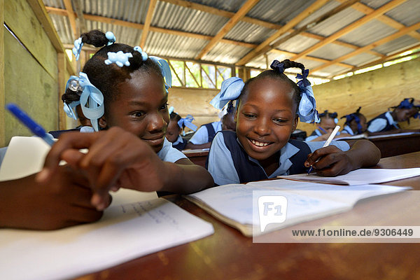 Two girls writing in a notebook  school for earthquake refugees  Fort National  Port-au-Prince  Haiti