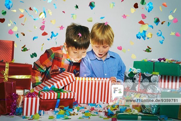 Zwei Brüder öffnen Mund auf Auspacken glühenden Weihnachtsgeschenkbox mit explodierenden Konfetti