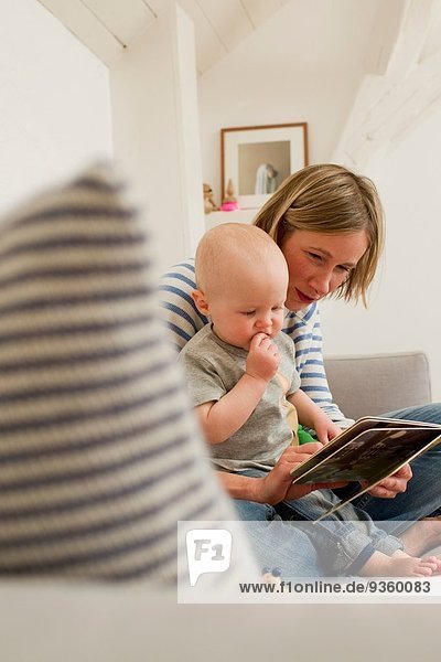 Reife Mutter und Tochter lesen Märchenbuch auf dem Wohnzimmersofa