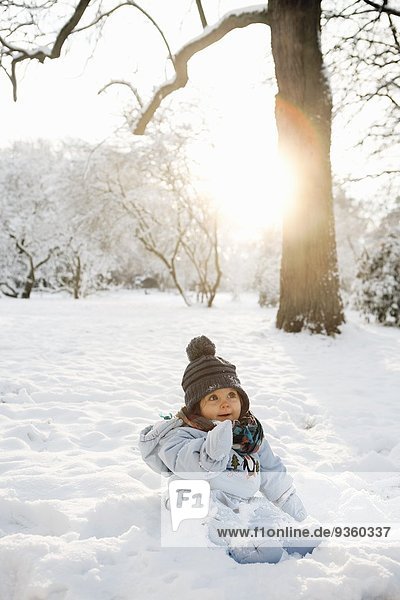 Junges Mädchen im Schnee sitzend