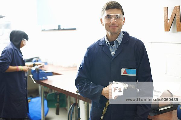 Portrait of male student with hand drill in college metalwork workshop