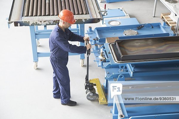 Worker using manual pallet jack in industrial plant