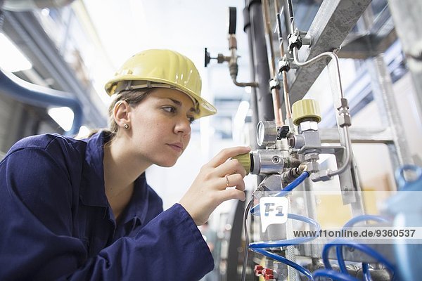 Female engineer checking cables on industrial machinery