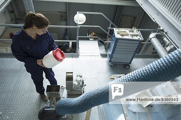 High angle view of factory worker reading instructions on plastic container