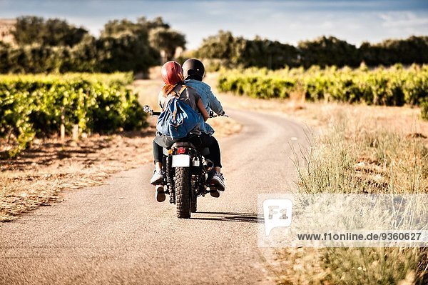 Rear view of mid adult couple riding motorcycle on winding rural road  Cagliari  Sardinia  Italy