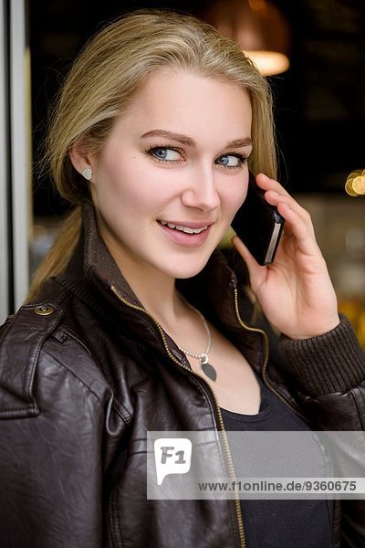 Junge Frau beim Plaudern auf dem Smartphone im Café-Tor