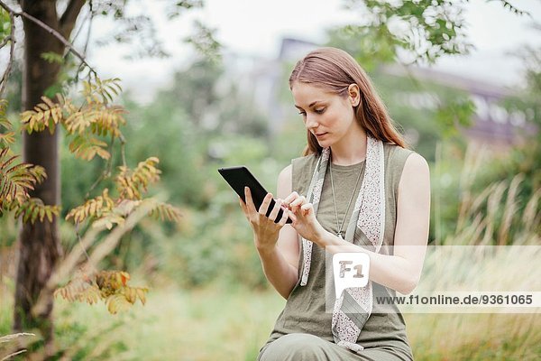 Junge Frau mit digitalem Tablett im Feld