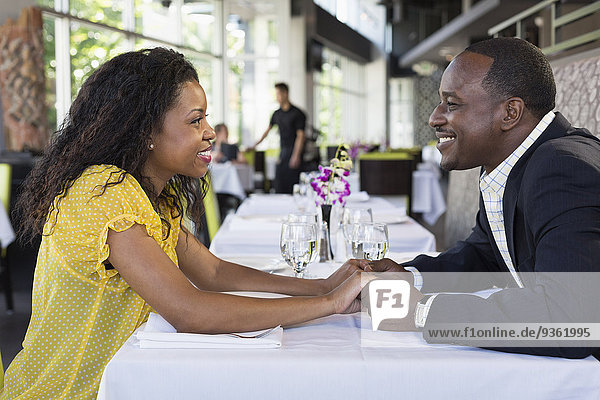 African American couple holding hands in restaurant