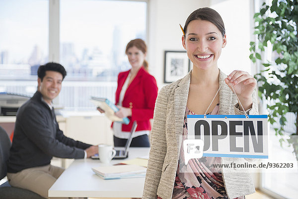 Businesswoman holding Open sign in office