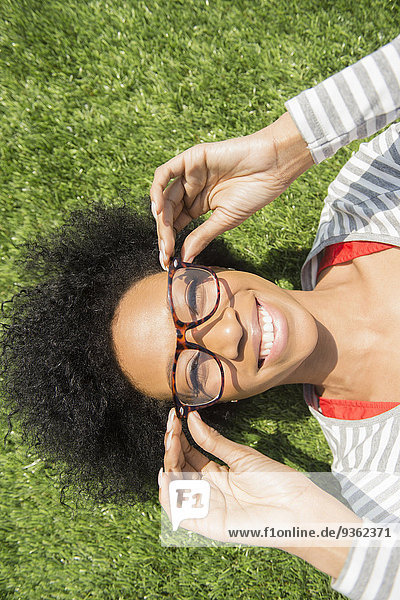 African American woman laying in grass wearing eyeglasses
