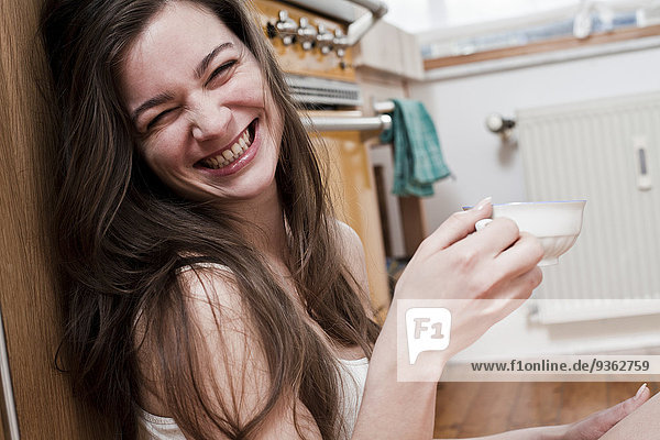 Portrait of smiling young woman with cup of tea at home