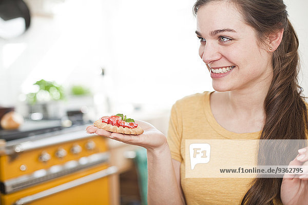 Junge Frau mit Erdbeertartelett auf der Hand