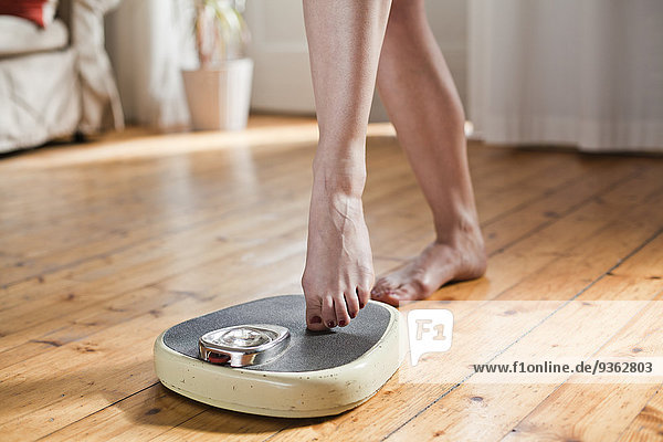 Woman testing personal scales  partial view