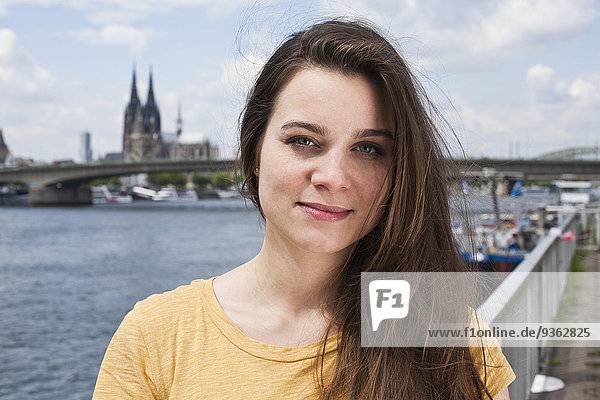 Germany  Cologne  portrait of smiling young woman standing in front of Rhine River
