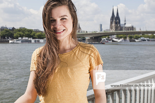 Deutschland  Nordrhein-Westfalen  Köln  Portrait einer lächelnden jungen Frau vor dem Rhein
