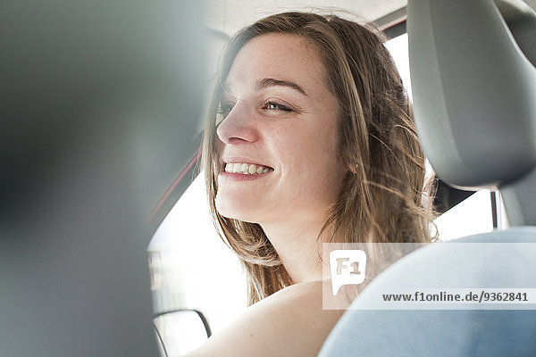 Porträt einer lächelnden jungen Frau  die in einem Auto sitzt