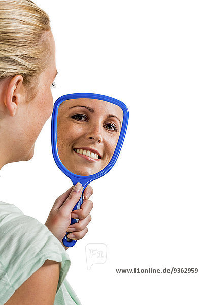 Lächelnde junge Frau schaut in den Spiegel