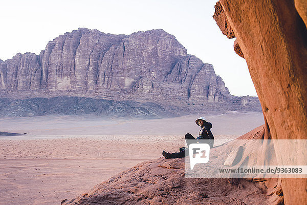 Jordan  Japanerin sitzt auf einem Felsen im Wadi Rum