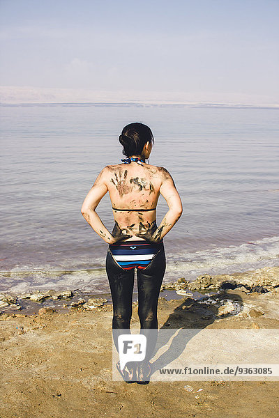Jordan  Japanerin mit Totes Meer Schlamm auf ihrem Unterkörper an einem Strand auf der jordanischen Seite des Toten Meeres