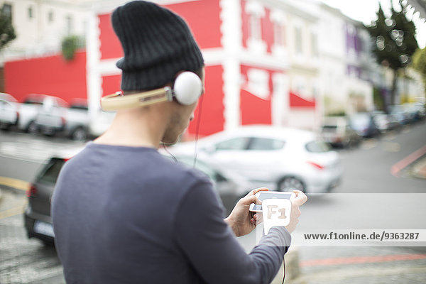 Junger Mann mit Kopfhörer und Smartphone beim Musikhören
