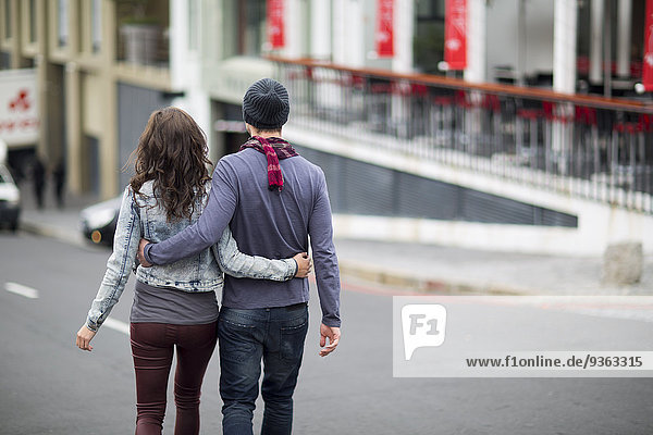 Junges Paar geht Arm in Arm auf der Straße.