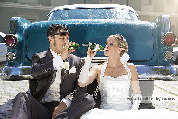 Brautpaar trinkt Piccolo vor dem Oldtimer