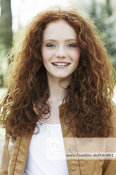 Porträt eines lächelnden Mädchens mit lockigen roten Haaren