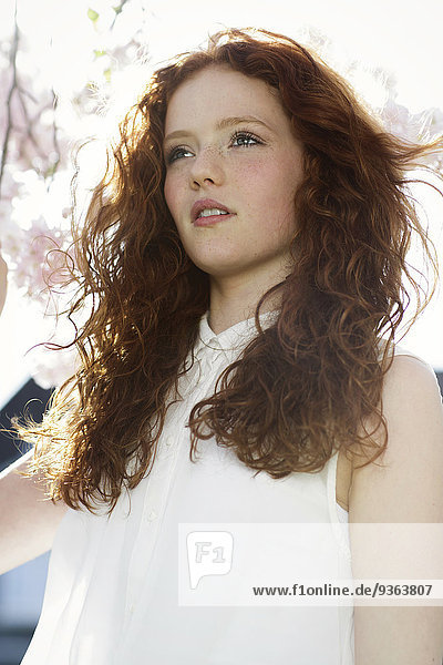 Portrait of girl with curly red hair wearing white dress