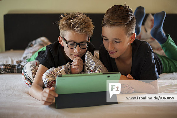 Zwei Jungen auf dem Bett liegend mit Digital-Tablett