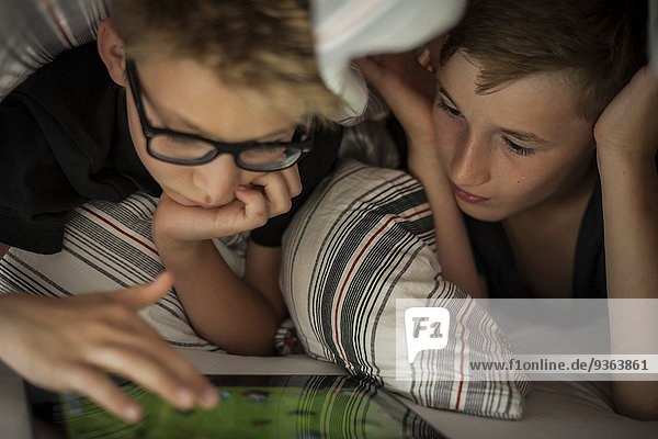 Zwei Jungen auf dem Bett liegend mit Digital-Tablett