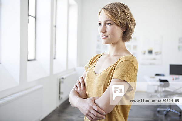 Portrait of young woman with crossed arms in a creative office