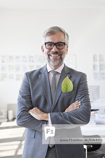 Portrait of smiling businessman with green leaf in his jacket pocket