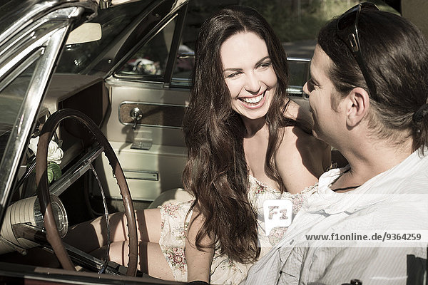 Happy couple sitting in vintage car convertible