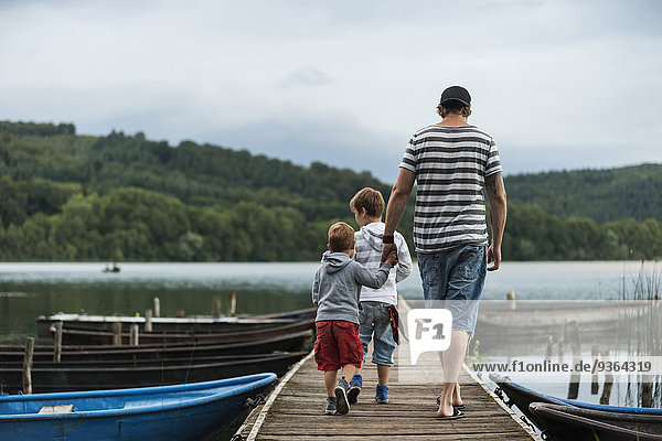 Germany  Rhineland-Palatinate  Laacher See  father walking with two sons on jetty