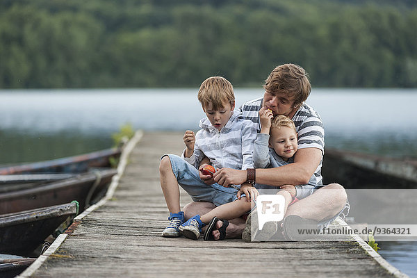 Deutschland  Rheinland-Pfalz  Laacher See  Vater sitzend mit zwei Söhnen am Steg