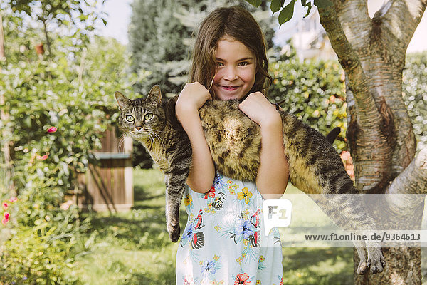 Mädchen hält Katze im Garten
