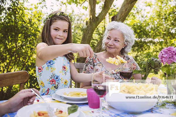 Mädchen serviert Nudeln an Großmutter auf Gartenparty