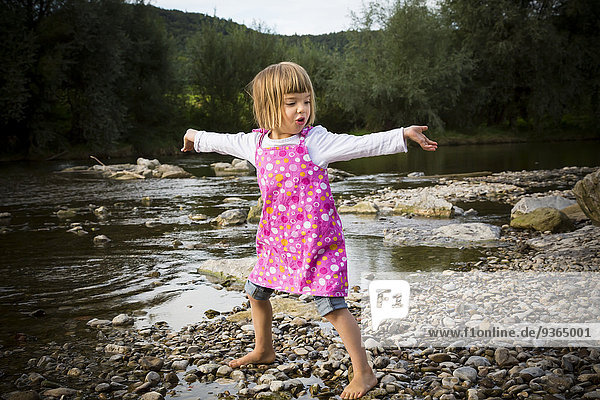 Kleines Mädchen tanzt am Flussufer