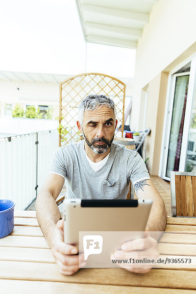 Porträt eines Mannes mit digitalem Tablett auf dem Balkon