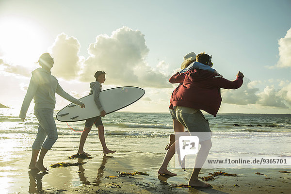 Frau und drei Teenager  die am Ufer des Meeres spazieren gehen.
