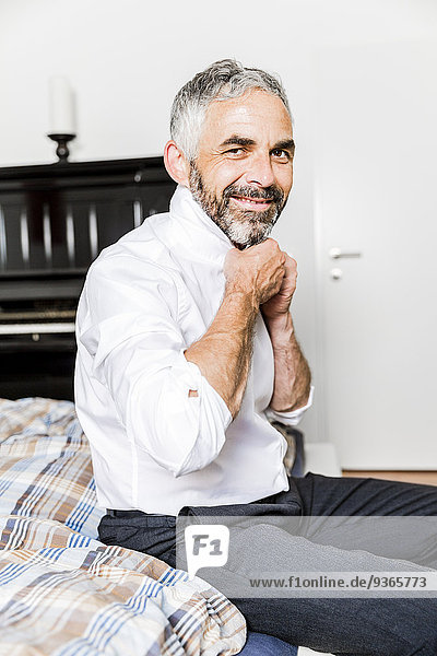 Porträt eines lächelnden Geschäftsmannes mit Krawatte im Schlafzimmer