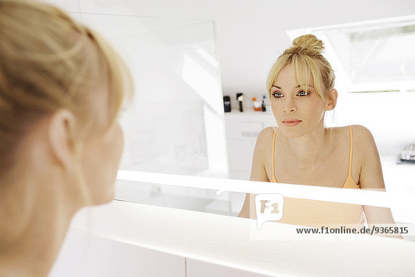 Frau betrachtet ihr Spiegelbild im Bad