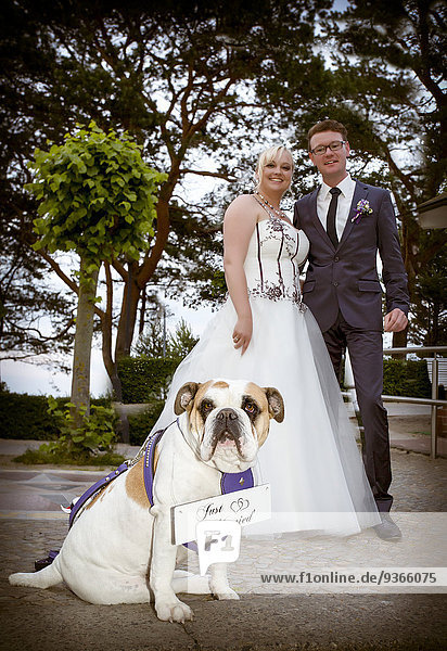 Glückliches Brautpaar mit englischer Bulldogge im Vordergrund