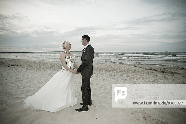 Deutschland  Mecklenburg-Vorpommern  Rügen  Sellin  Brautpaar stehen Hand in Hand am Strand