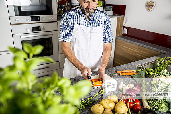 Österreich  Mann in der Küche zerkleinert Karotten